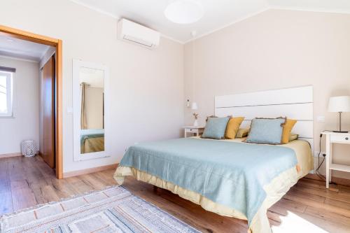 a white bedroom with a large bed with blue pillows at Windmill Escape - Onda Townhouse in Odeceixe