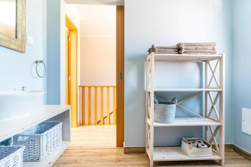 La salle de bains est pourvue de murs bleus et d'une étagère en bois. dans l'établissement Windmill Escape - Onda Townhouse, à Odeceixe