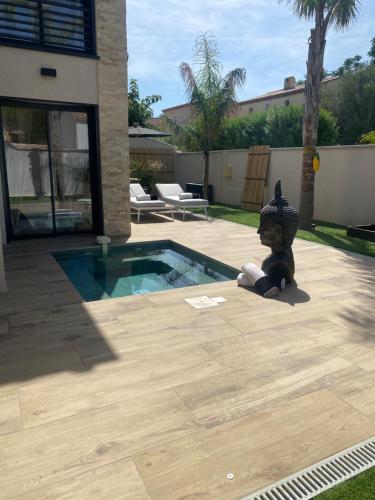 un ours en peluche allongé sur le sol à côté d'une piscine dans l'établissement Villa Natural Zen Rayolet, à Six-Fours-les-Plages