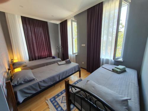 a bedroom with two beds and two windows at Velio Guest House in Velistsʼikhe