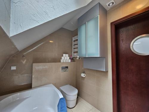 uma casa de banho com uma banheira branca e um WC. em Krakowska 1 em Pobierowo