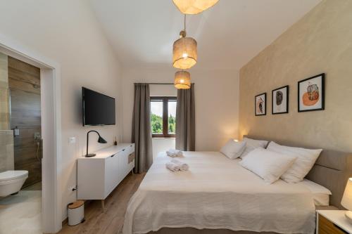 a bedroom with a bed and a television and a bathroom at Old Oak Villa in Umag