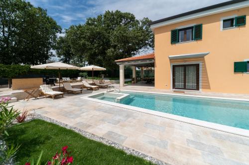 a villa with a swimming pool and a patio at Old Oak Villa in Umag