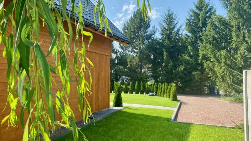 a house with a green yard with a building at Domki Dream Home in Polanica-Zdrój