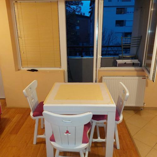 a table and chairs in a room with a window at Apartman Alisa in Kruševac