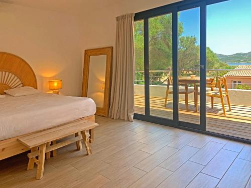 a bedroom with a bed and a balcony with a table at Hôtel Maora Village in Bonifacio
