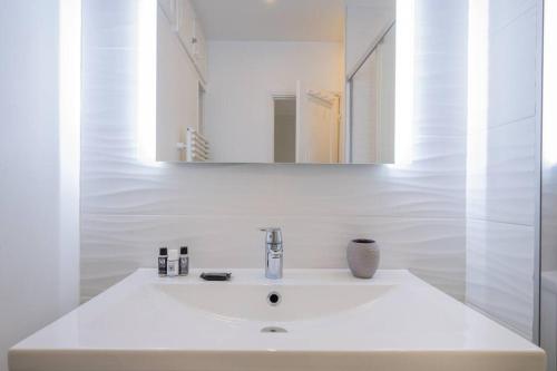 une salle de bain blanche avec un lavabo et un miroir dans l'établissement Goujon - Cozy apartment in Nation-Picpus neighborhood, à Paris