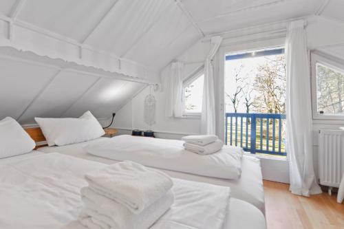 2 weiße Betten in einem Zimmer mit Fenster in der Unterkunft See-Chalet Riederau in Dießen am Ammersee