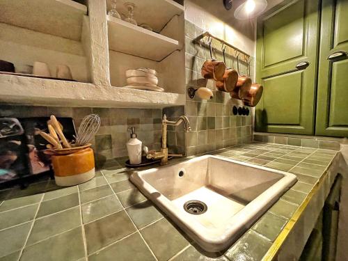 - une cuisine avec un évier et des placards verts dans l'établissement MAISON DES SARRASINS, à Ramatuelle