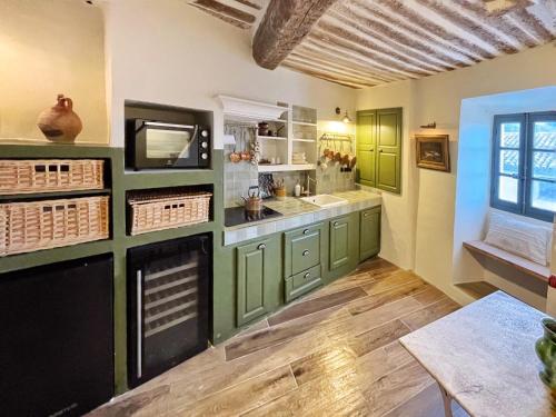 a kitchen with green cabinets and a fireplace at MAISON DES SARRASINS in Ramatuelle