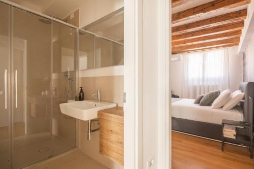 a bathroom with a sink and a shower and a bed at Ruga Bella Apartments R&R in Venice