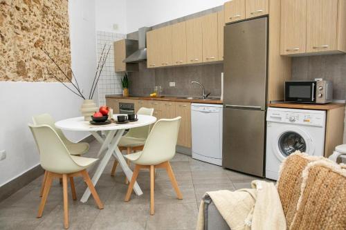 cocina con mesa, sillas y nevera en Apartamentos Casa Macías, en Cádiz