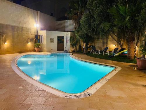 a large swimming pool in a courtyard at night at Malta Villa in Naxxar