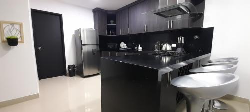 a black kitchen with two sinks and a refrigerator at Equilibrio Shalom Living in Medellín