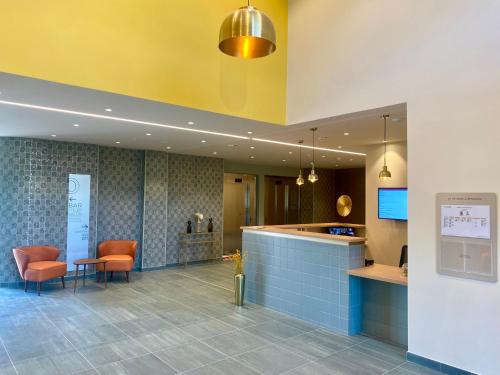 a lobby with orange chairs and a counter in a building at DOMITYS LES SEQUANES in Chalon-sur-Saône