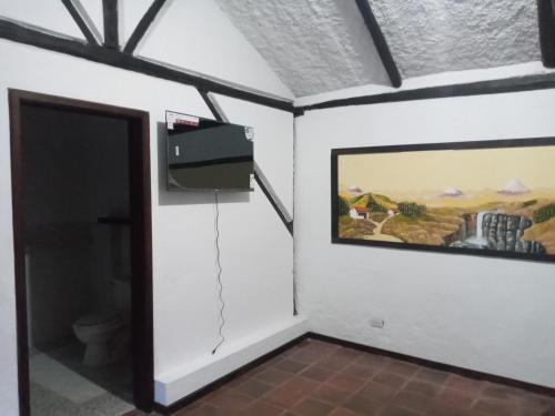 een kamer met een schilderij aan de muur en een deur bij Quinta los Eucaliptos in Quito