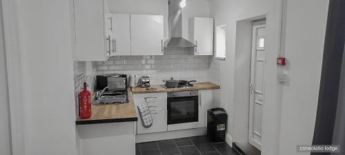 a kitchen with white cabinets and a stove top oven at Consolatio Lodge in Great Yarmouth