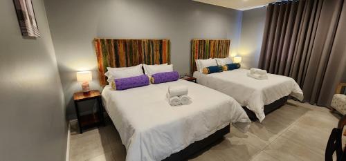 a bedroom with two beds with white sheets and purple pillows at Chai & Spice Guesthouse and Café in George