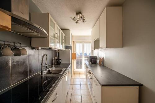 une cuisine avec des armoires blanches et un comptoir noir dans l'établissement Ivry - Family apartment at the Gates of Paris, à Ivry-sur-Seine
