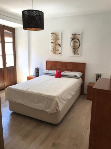 um quarto com uma cama com uma almofada vermelha em WADI DAR AL-FARAH, ( LA CASA DE LA ALEGRIA DE GUADIX) em Guadix