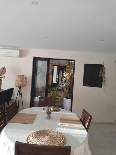 a dining room table with a white table cloth and chairs at Superbe appartement au calme avec piscine in Montagnac