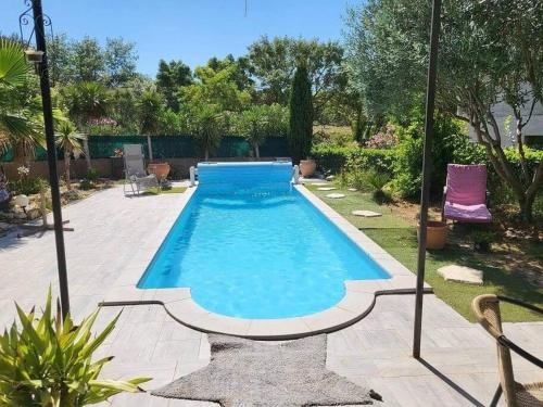 a swimming pool in a yard with a purple chair at Superbe appartement au calme avec piscine in Montagnac