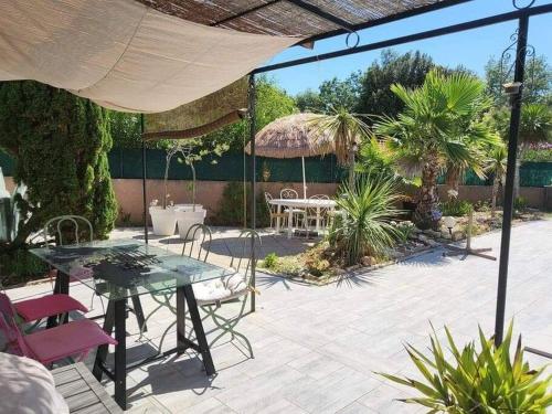 a patio with a table and chairs on a patio at Superbe appartement au calme avec piscine in Montagnac