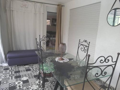 a glass table and chairs in a living room at Superbe appartement au calme avec piscine in Montagnac