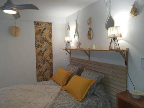 a bedroom with a bed with yellow pillows and two lamps at Superbe appartement au calme avec piscine in Montagnac