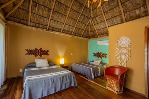 a bedroom with two beds and a red chair at Amaca Beach Hotel - Eco Resort Quiimixto in Qumiste