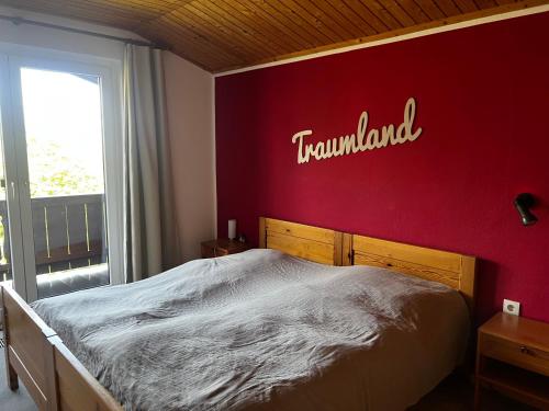 a bedroom with a red wall with the word tumushima at Ferienhaus Hochkönigblick in Leogang