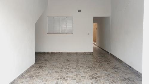 an empty room with a white wall and a tile floor at Casa Miríades in Hortolândia