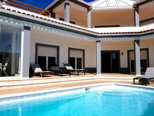a villa with a swimming pool and a patio at Praia d'el Rey The Golf & Beach Villa in Óbidos