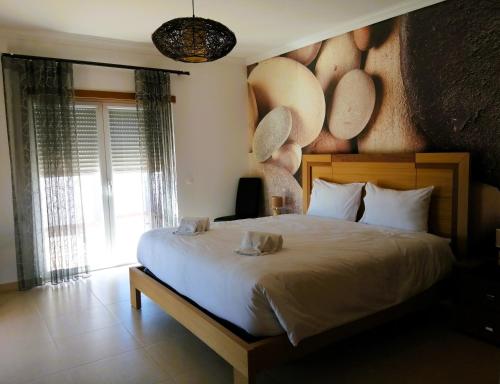 a bedroom with a large bed and a large window at Praia d'el Rey The Golf & Beach Villa in Óbidos