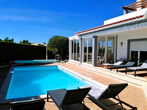 a swimming pool with chairs and a house at Praia d'el Rey The Golf & Beach Villa in Óbidos