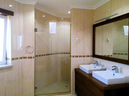 a bathroom with a shower and two sinks and a mirror at Praia d'el Rey The Golf & Beach Villa in Óbidos