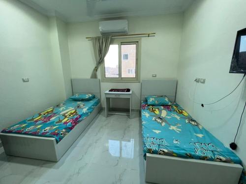 a bedroom with two beds and a desk and a window at Moon light Hotel in Kafr Mas‘ūd
