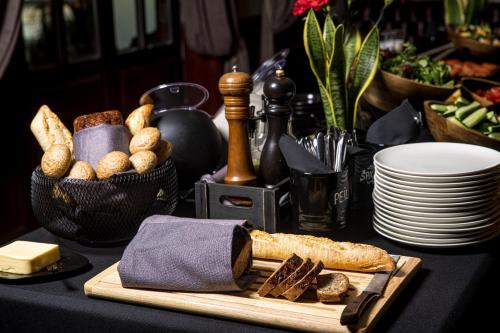 a table topped with bread and a cutting board with cheese at Senoji Hansa Hotel in Palanga