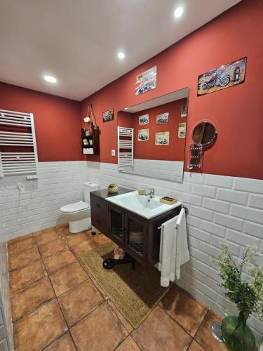 a bathroom with red walls and a sink and a toilet at Apartamento Mikaela Alcalá de Henares in Alcalá de Henares