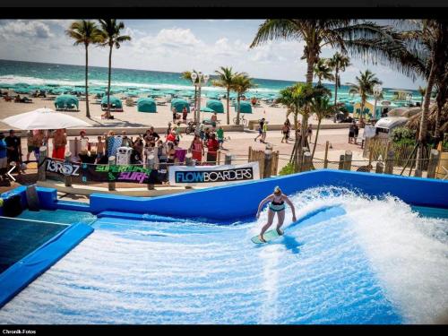 une femme faisant une vague sur une planche de surf dans une piscine à la plage dans l'établissement 322 Cool Beach Studio, à Hollywood