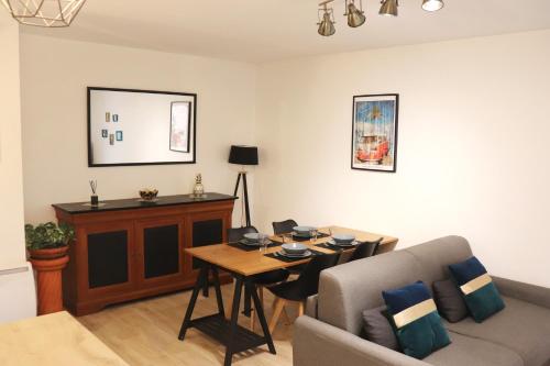 a living room with a table and a couch at Le Chapitre Spacieux - parking en résidence fermée in Toulouse