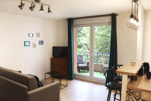 a living room with a couch and a sliding glass door at Le Chapitre Spacieux - parking en résidence fermée in Toulouse