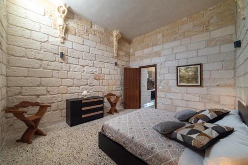 1 dormitorio con cama y pared de piedra en Il colore del Salento, en Carpignano Salentino