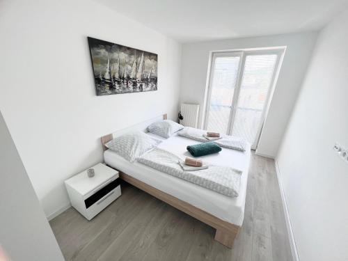 a white bedroom with a bed and a window at City center apartment with nice balcony in Žilina