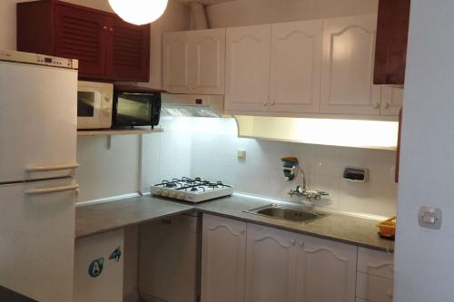 a kitchen with white cabinets and a sink and a refrigerator at Bodrum Center Private Holiday House in Bodrum City