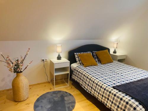 1 dormitorio con 1 cama y un jarrón con flores en Scenic Chalet Malowniczy Domek, en Szlembark