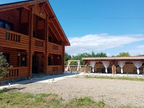 eine große Holzscheune mit einem Pavillon daneben in der Unterkunft Casa Ilies in Rozavlea