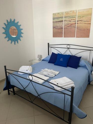 a blue bed with blue pillows and a clock on the wall at Villa Imma in Torre Lapillo