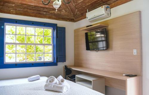 a bedroom with a bed and a desk and a window at Flat com Piscina no Centro de Tiradentes in Tiradentes