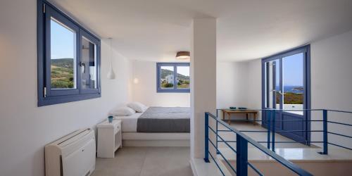 a white bedroom with a bed and two windows at White Dream Suites Antiparos in Antiparos